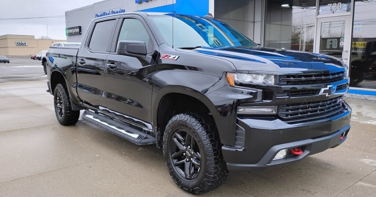  A black 2020 Chevrolet Silverado LT Trail Boss pickup truck is parked diagonally at Don's Chevrolet GMC in Wauseon, OH. The truck features a blacked-out grille with a blue Chevrolet bowtie logo, red recovery hooks, Z71 badging, and aggressive Goodyear Wrangler off-road tires on black alloy wheels. The background includes a dealership building with 