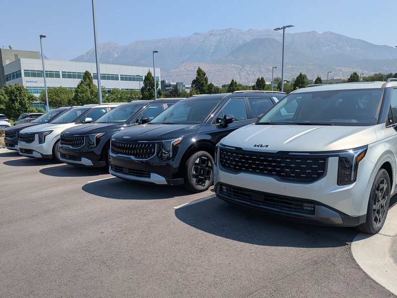 A row of vehicles on the Doug Smith Kia lot with the mountains behind