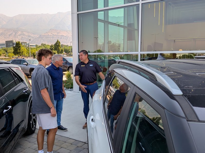 Customers and a salesperson beside a vehicle on the Doug Smith Kia lot