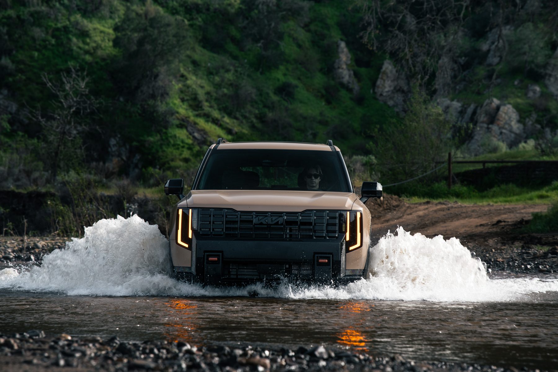 A 2027 Kia Telluride X-Pro driving through a shallow creek