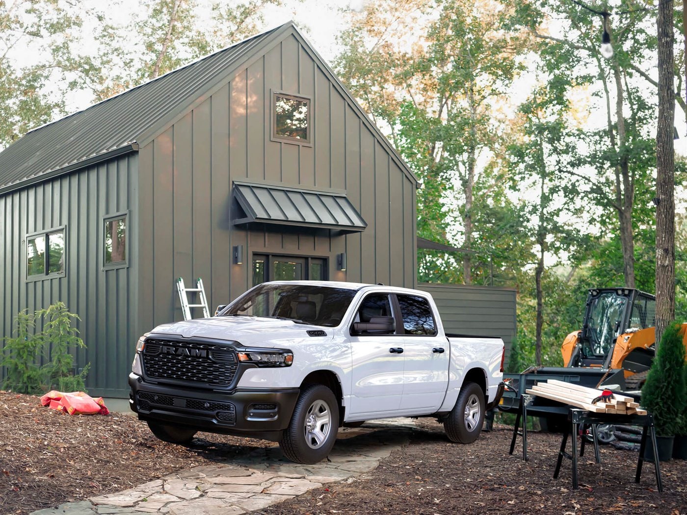 A white 2027 Ram 1500 Tradesman parked at a cabin under construction
