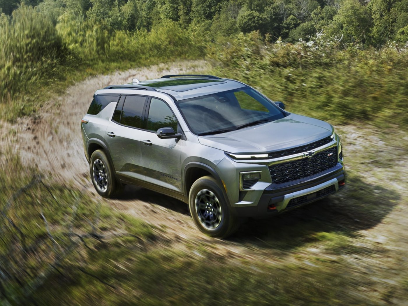 A Traverse Z71 driving a curving dirt road through tall grass