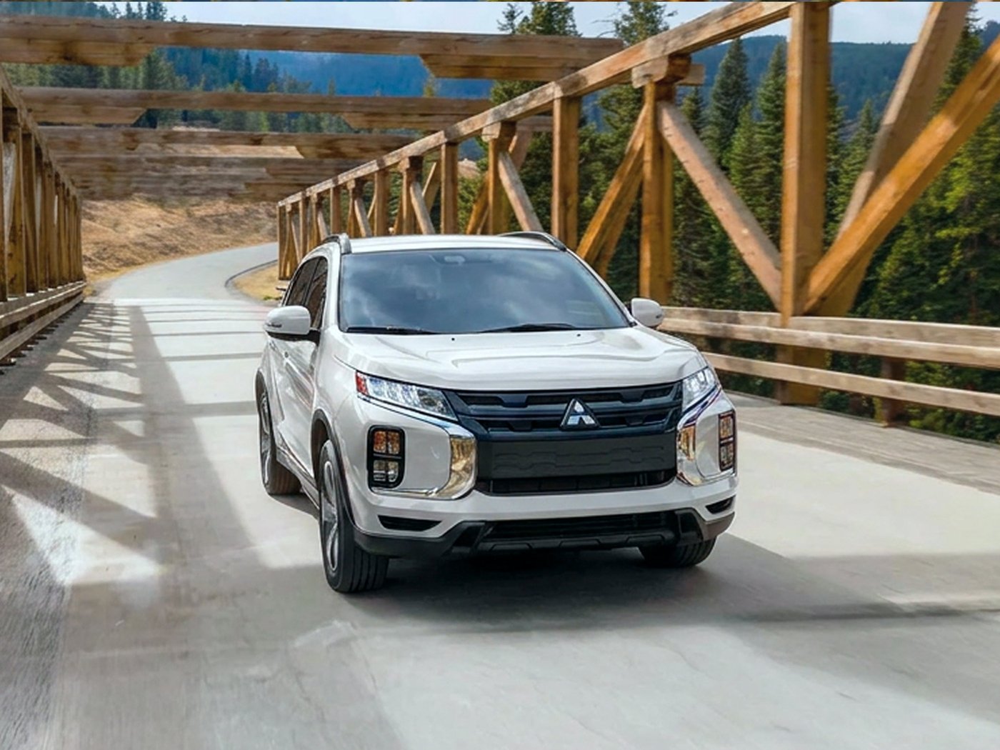 An Outlander Sport driving across a wooden truss bridge