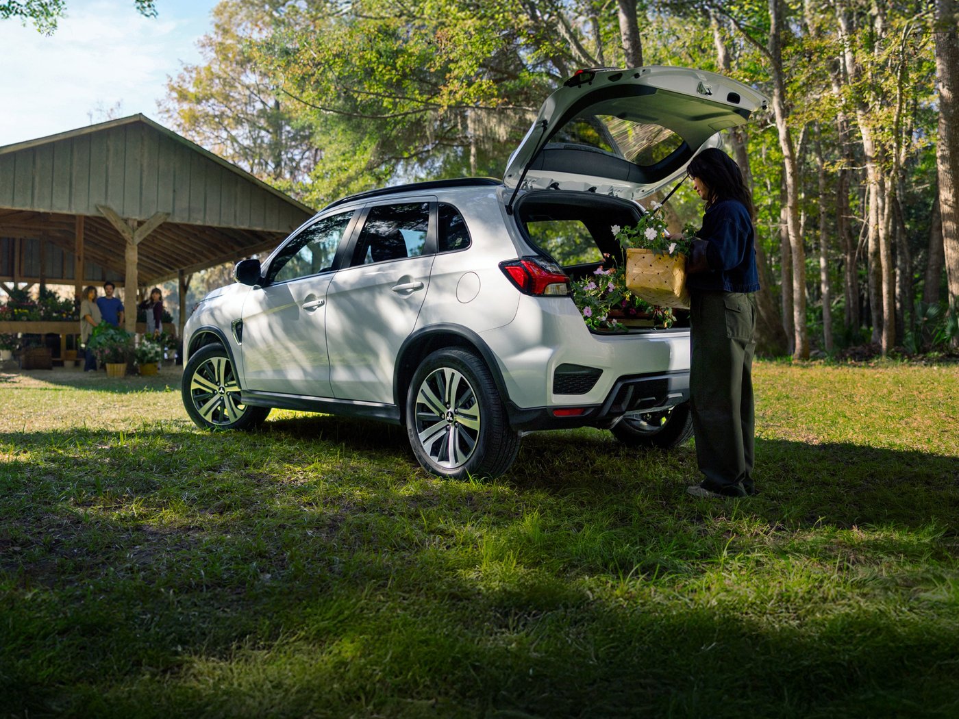 A shopper loading flowers into the open cargo area of a white Outlander Sport
