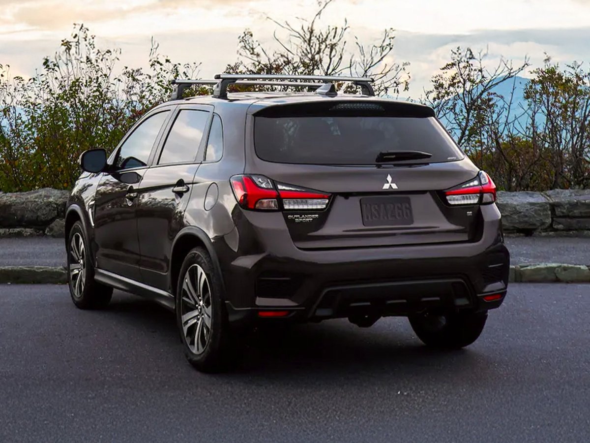 Rear three-quarter view of a brown Outlander Sport with roof rails at a mountain overlook