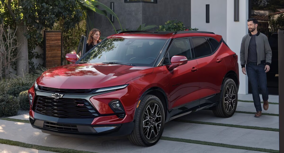  Driver and passenger getting into a red 2023 Chevy Blazer