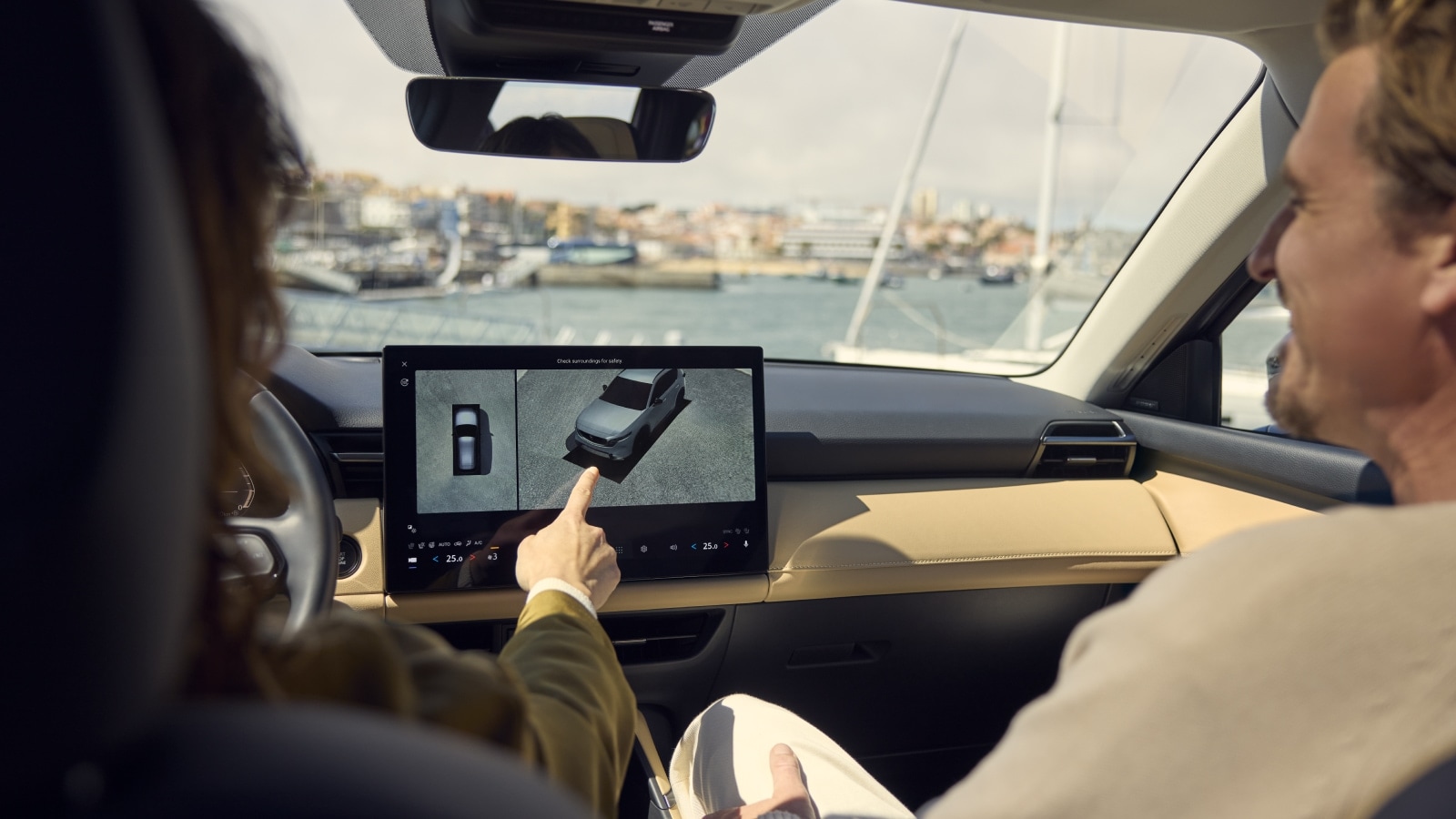 Couple driving a Mazda SUV and pointing out driver assistance tech