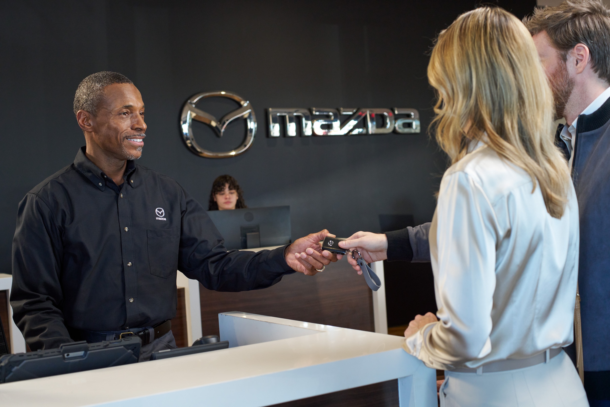 Mazda representative handing a keyfob to customers