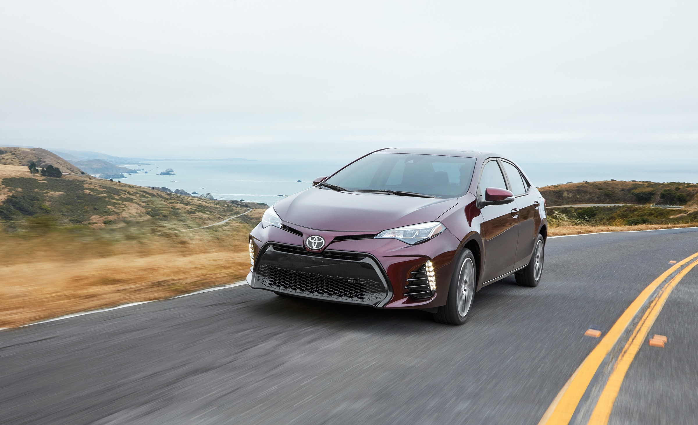Maroon 2018 Corolla driving on the coast