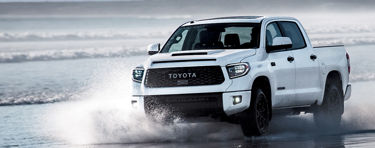 white Tundra driving in the shallow water on a beach