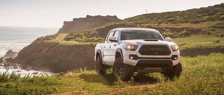 White 2019 Tacoma parked in front of a scenic coastal road