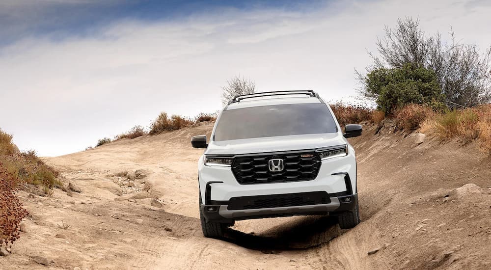 A white 2023 Honda Pilot Trailsport for sale is shown off-roading.