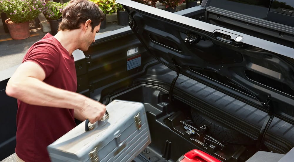 A man is shown putting cargo into the bed of a 2024 Honda Ridgeline RTL.