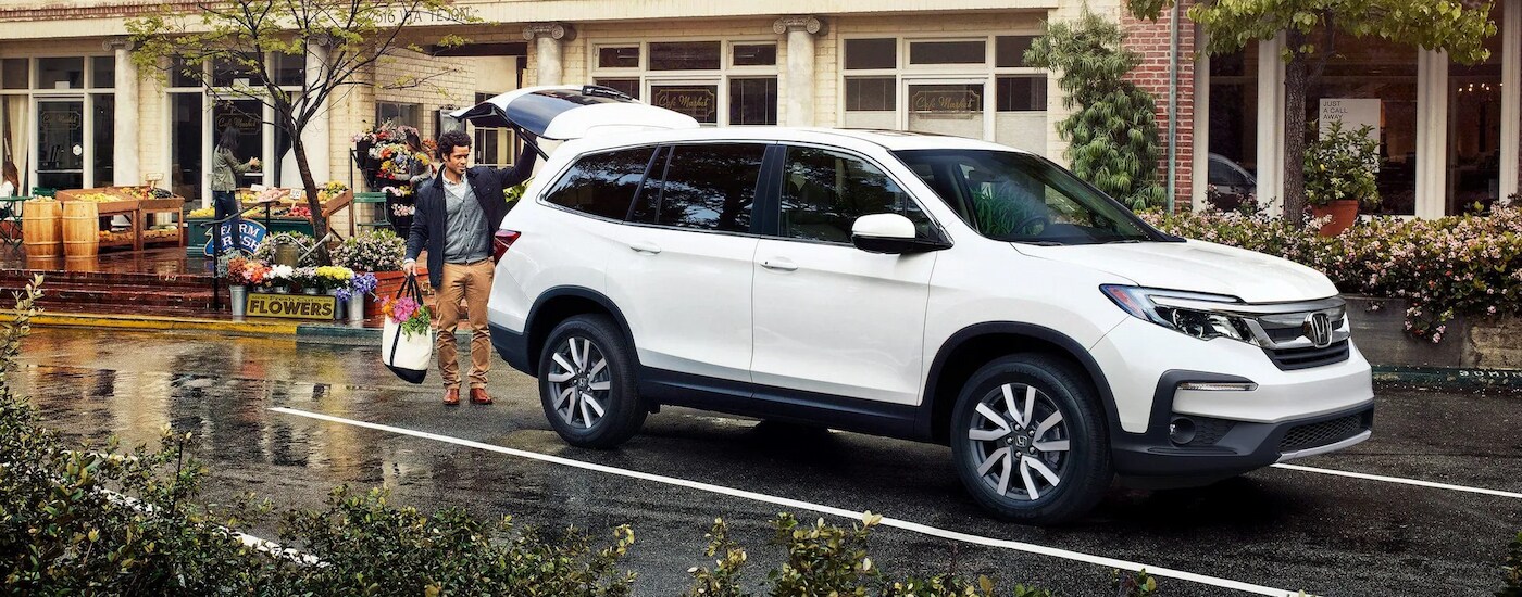 A white 2022 Honda Pilot EX-L is shown parked outside of flower shop after leaving a used Honda dealer.