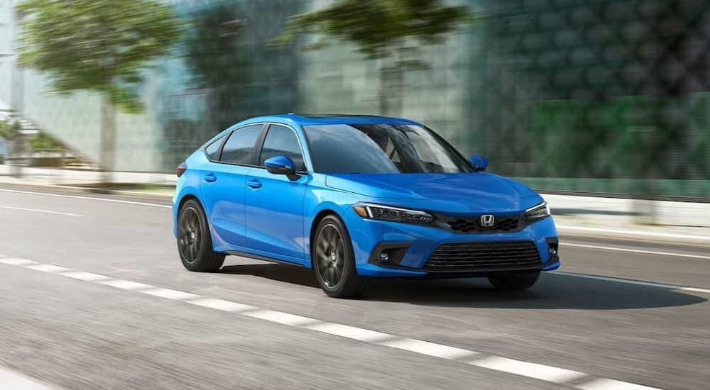 A blue 2024 Honda Civic for sale is shown driving on a city street.
