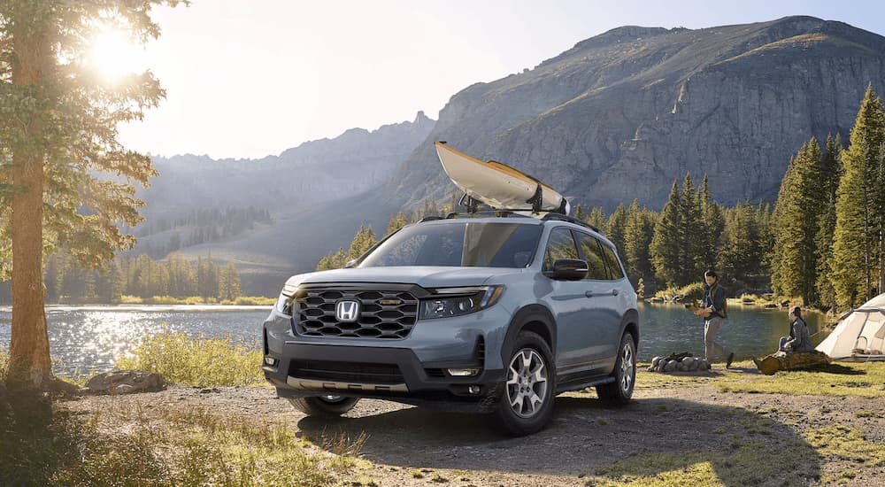 A grey 2023 Honda Passport Trailsport is shown with kayaks next to a lake.