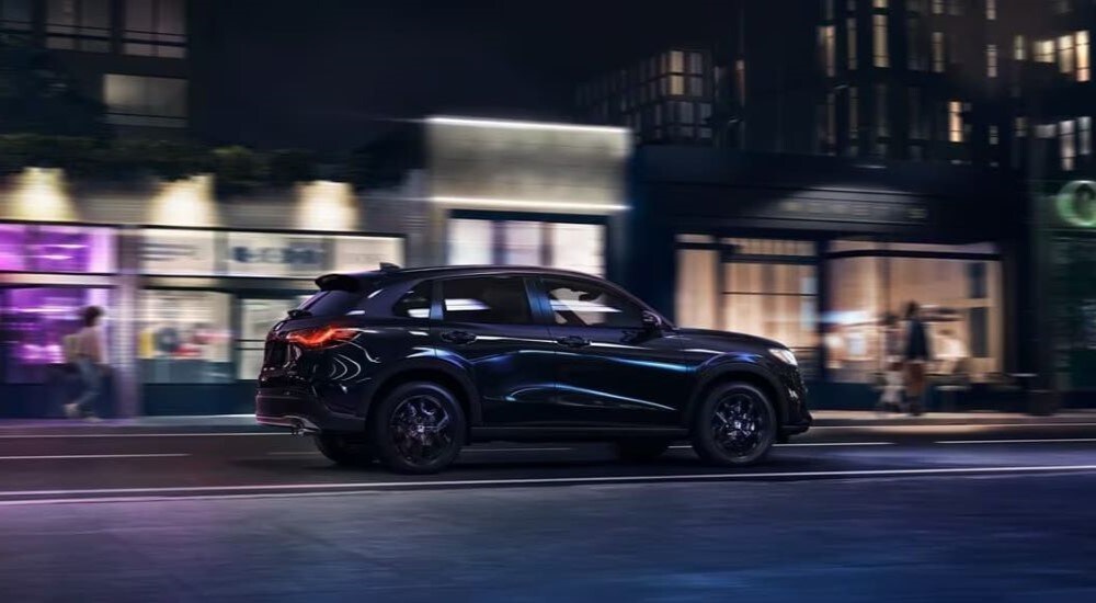 A black 2023 Honda HR-V Sport is shown on a city street at night.