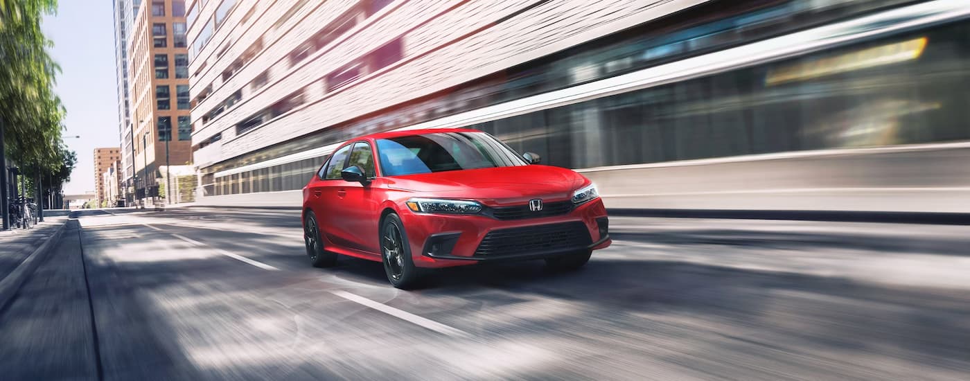 A red 2024 Honda Civic Sport is shown driving on a highway.