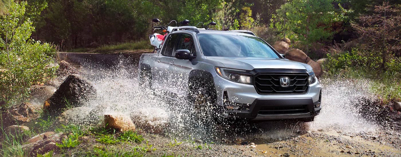 A grey 2022 Honda Ridgeline is shown splashing through a creek after leaving a Honda dealer in Monroe, LA.