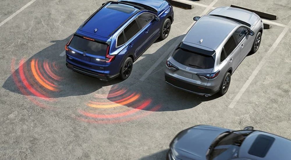 A close up shows simulated sensor lines coming from a dark blue 2023 Honda CR-V Sport Touring Hybrid.