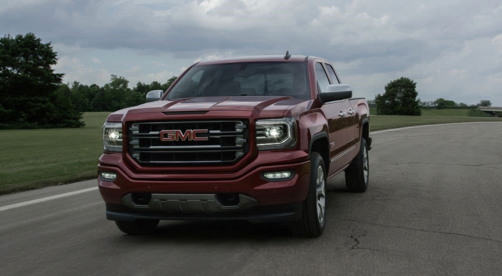 A red 2016 GMC Sierra 1500 All Terrain is shown driving on a road.