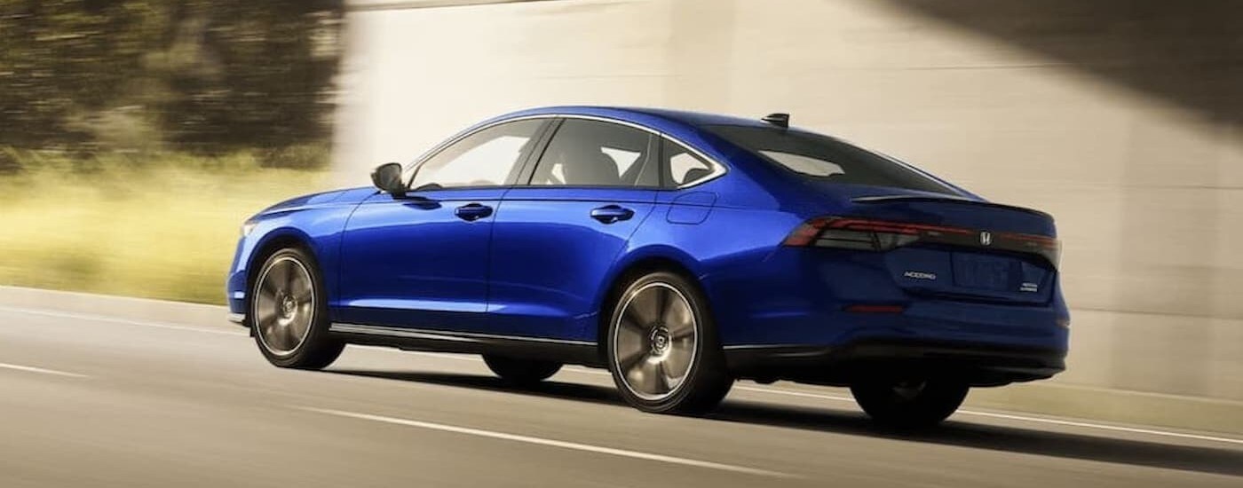 A blue 2023 Honda Accord Sport Touring is shown driving on a highway.