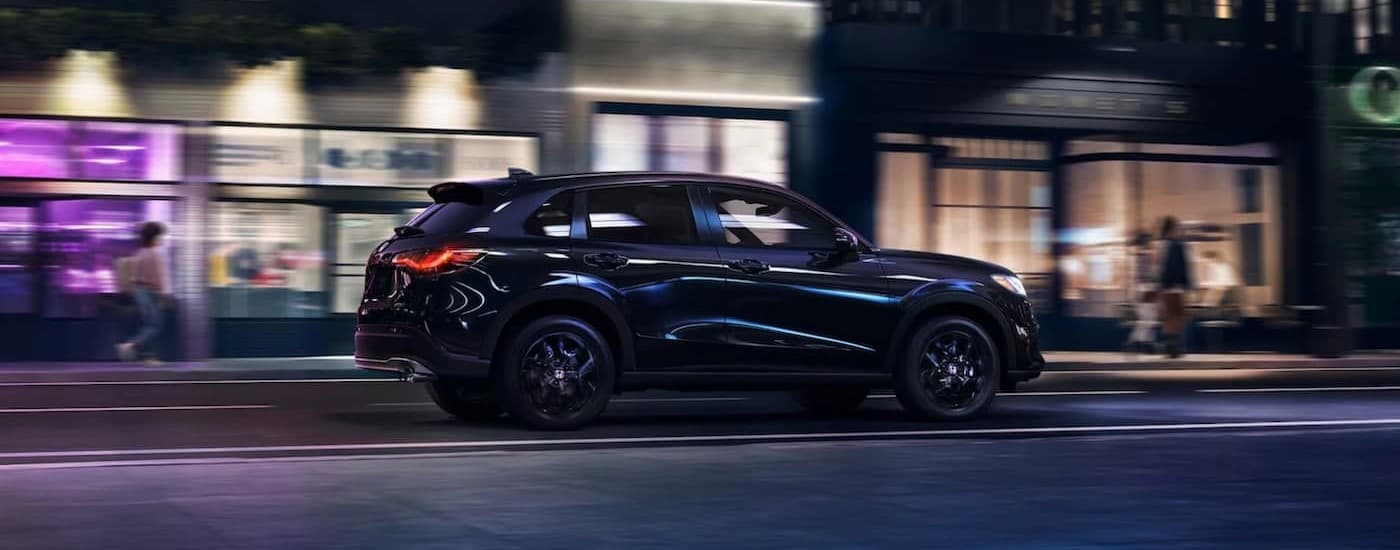 A black 2023 Honda HR-V is shown driving at night.
