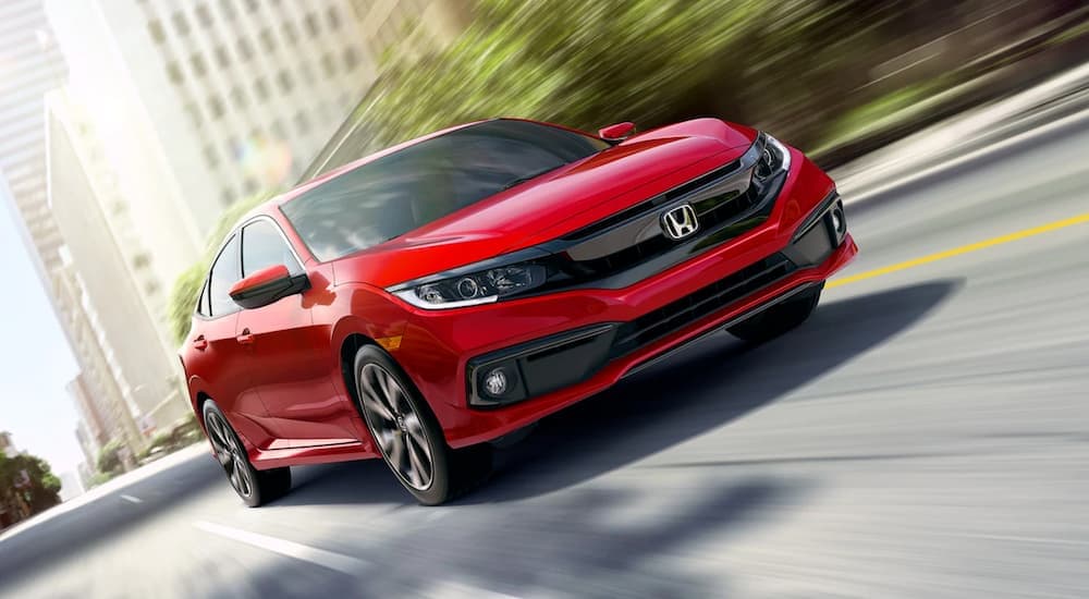 A red 2021 Honda Civic is shown driving on a city street.