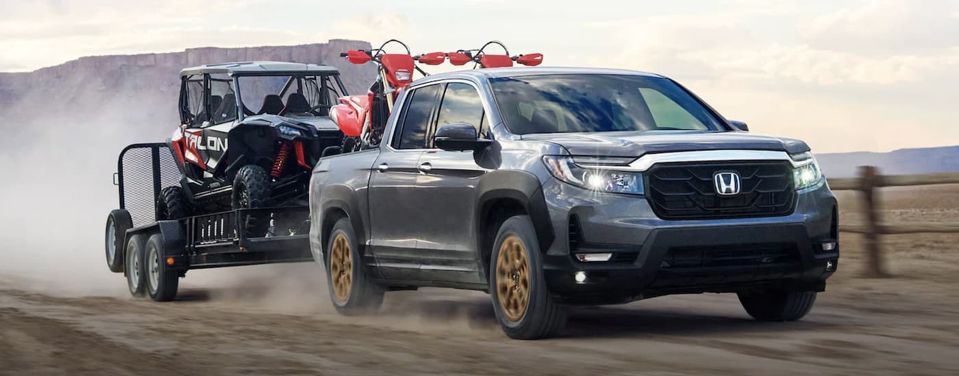 A grey 2022 Honda Ridgeline RTL towing a trailer with ATVs.