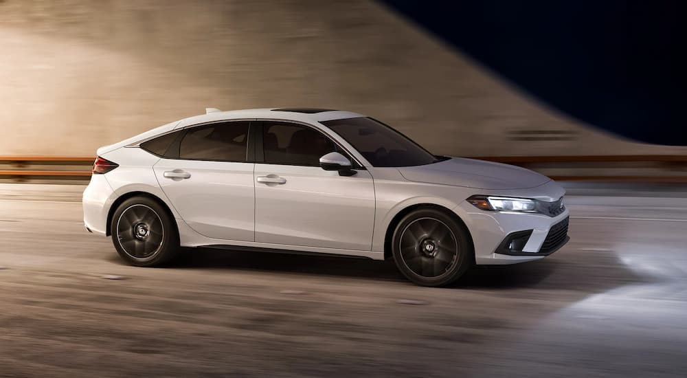 A white 2022 Honda Civic is shown driving to a used auto dealer.
