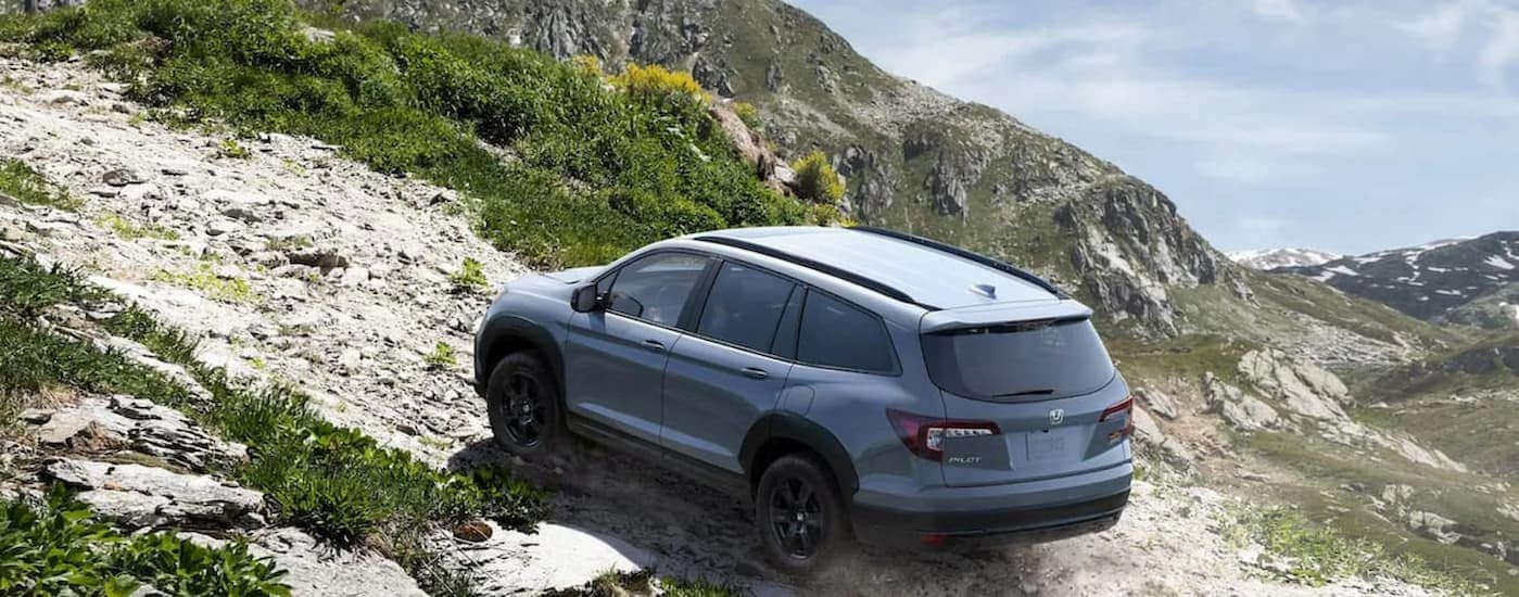 A blue 2022 Honda Pilot TrailSport is shown driving uphill.