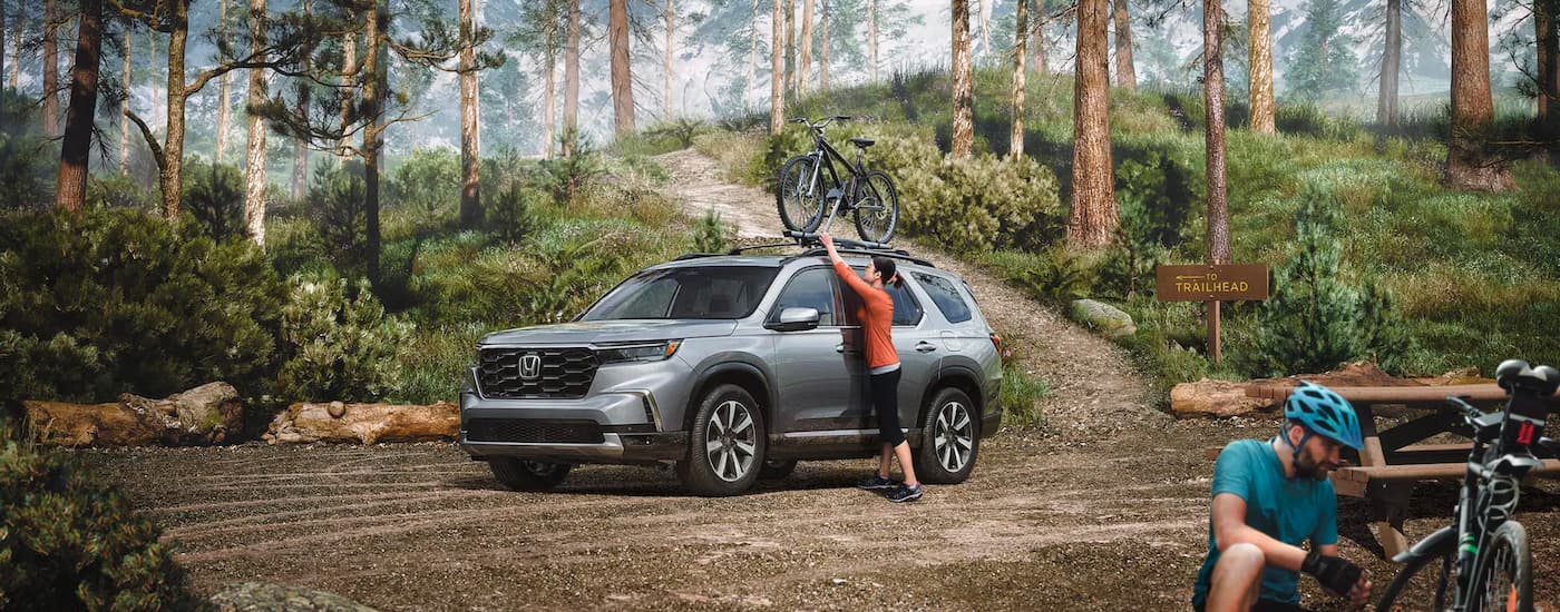 A silver 2023 Honda Pilot Touring is shown at a trailhead after leaving a Honda dealer near you.