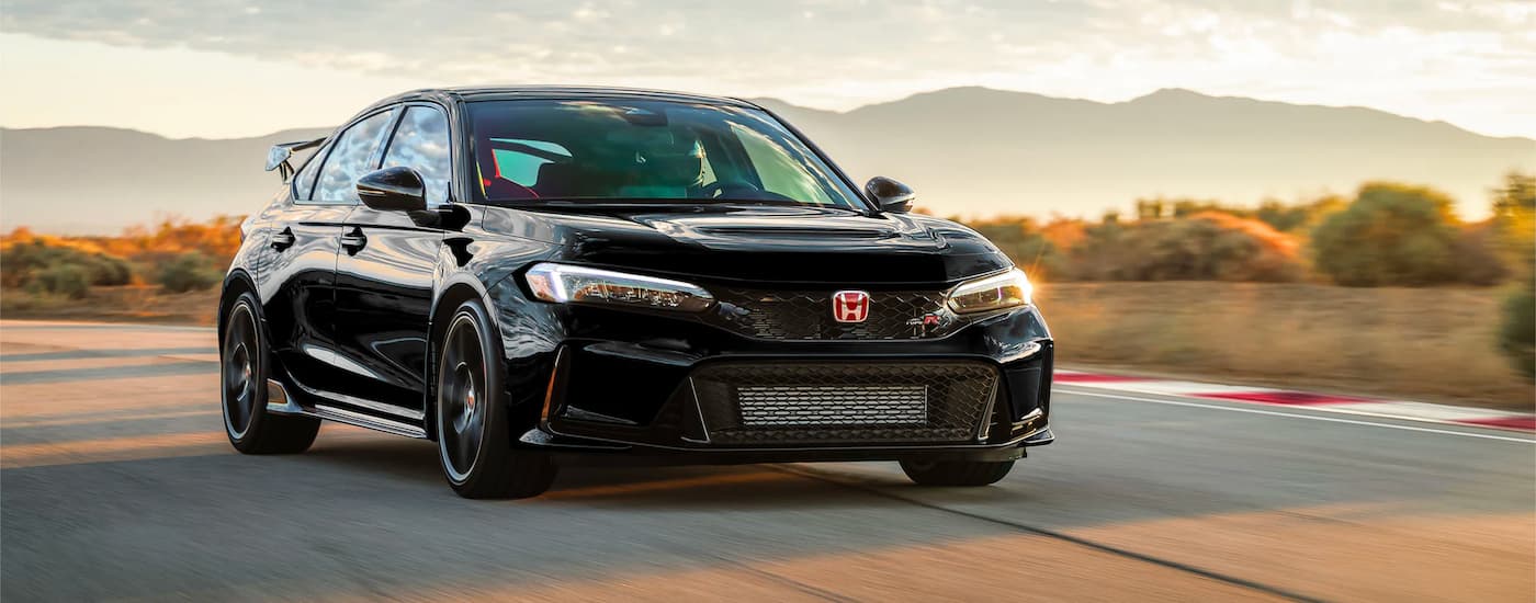 A black 2023 Honda Civic Type R is shown driving on an open road.