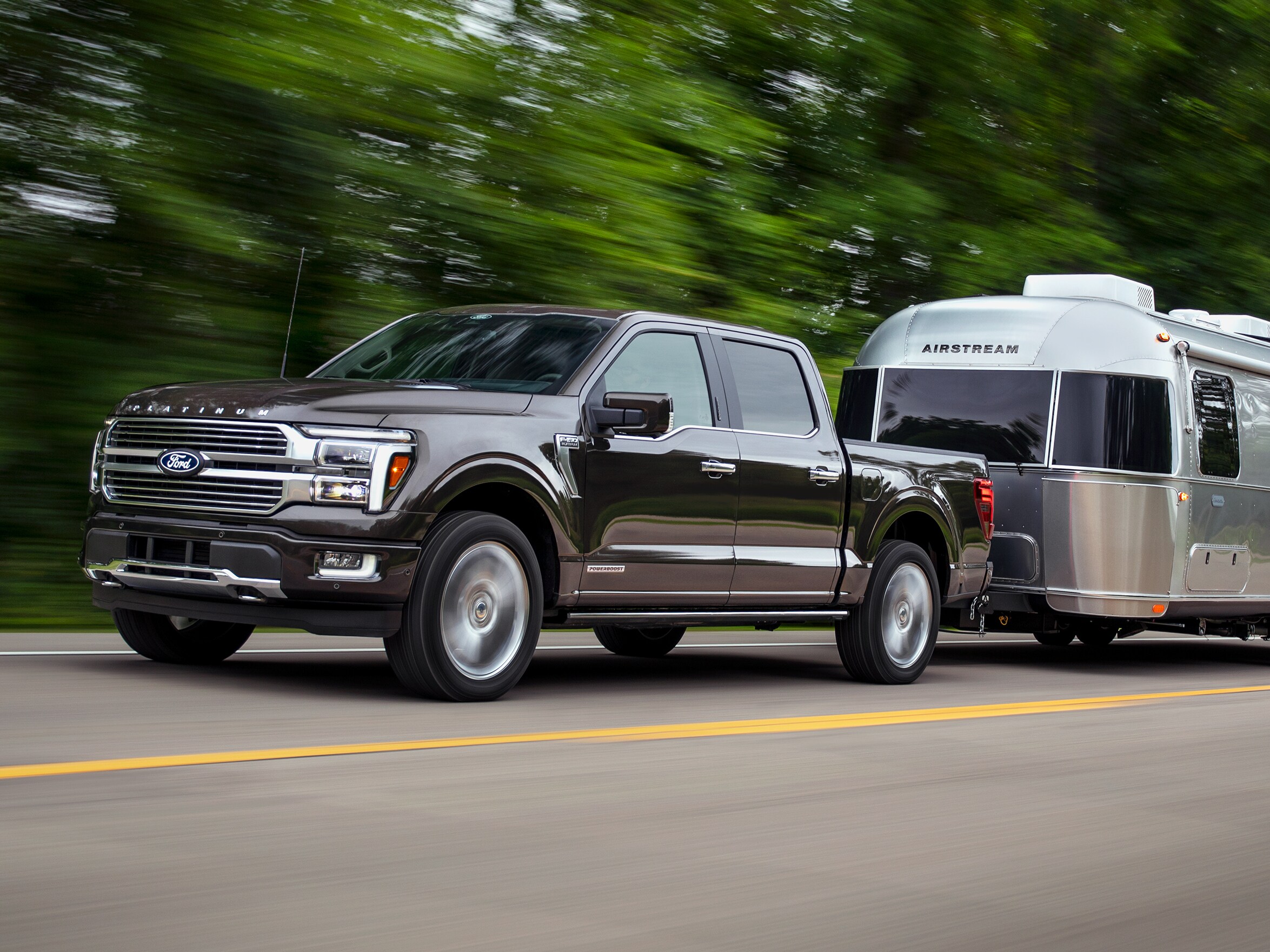 Two people exiting a 2025 Ford F-150® XLT pickup in Rapid Red hitched to a trailer of ATVs