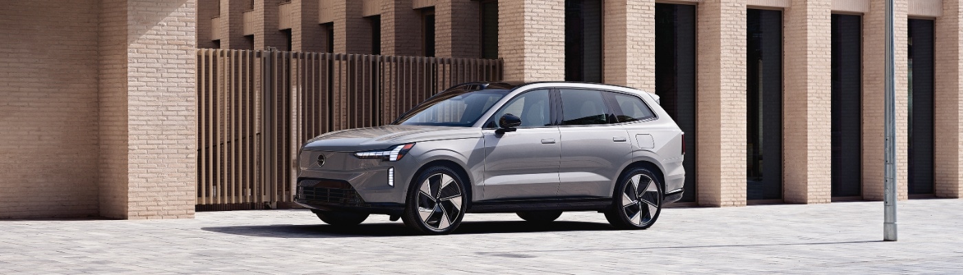 New Volvo EX90 parked next to light colored brick building