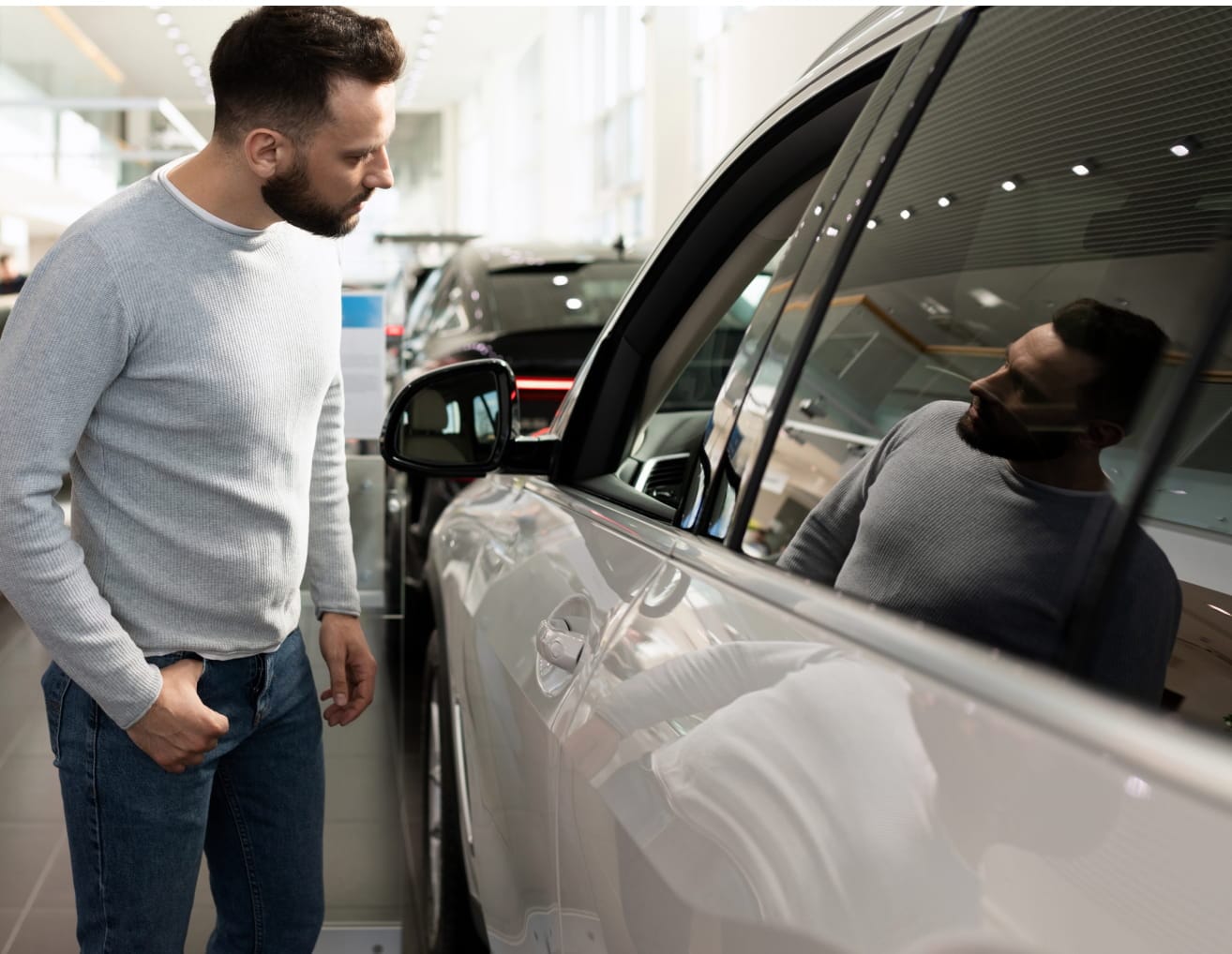 Customer examining a vehicle inside a car dealership showroom.