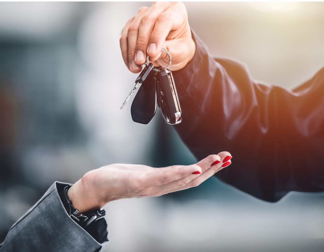 Car salesperson handing vehicle keys to a customer.