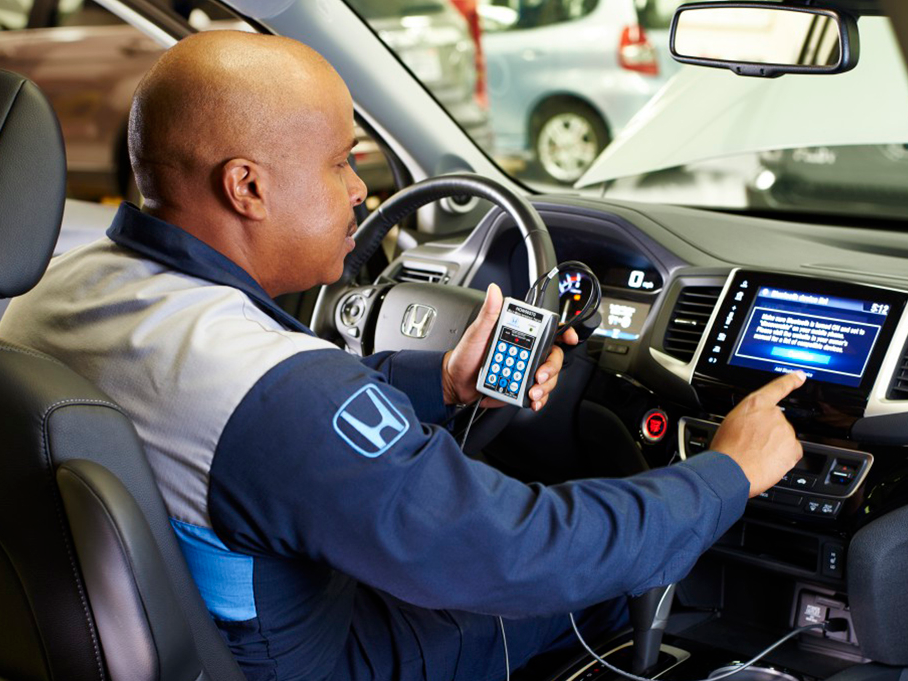 Honda service staff syncronizing a vehicle's tech system with their remote control