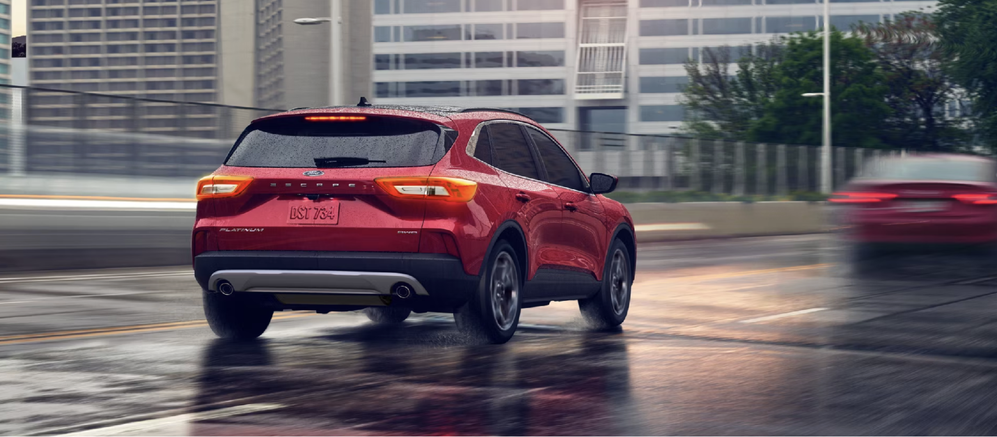 Ford Escape Platinum AWD driving on a wet city street at dusk