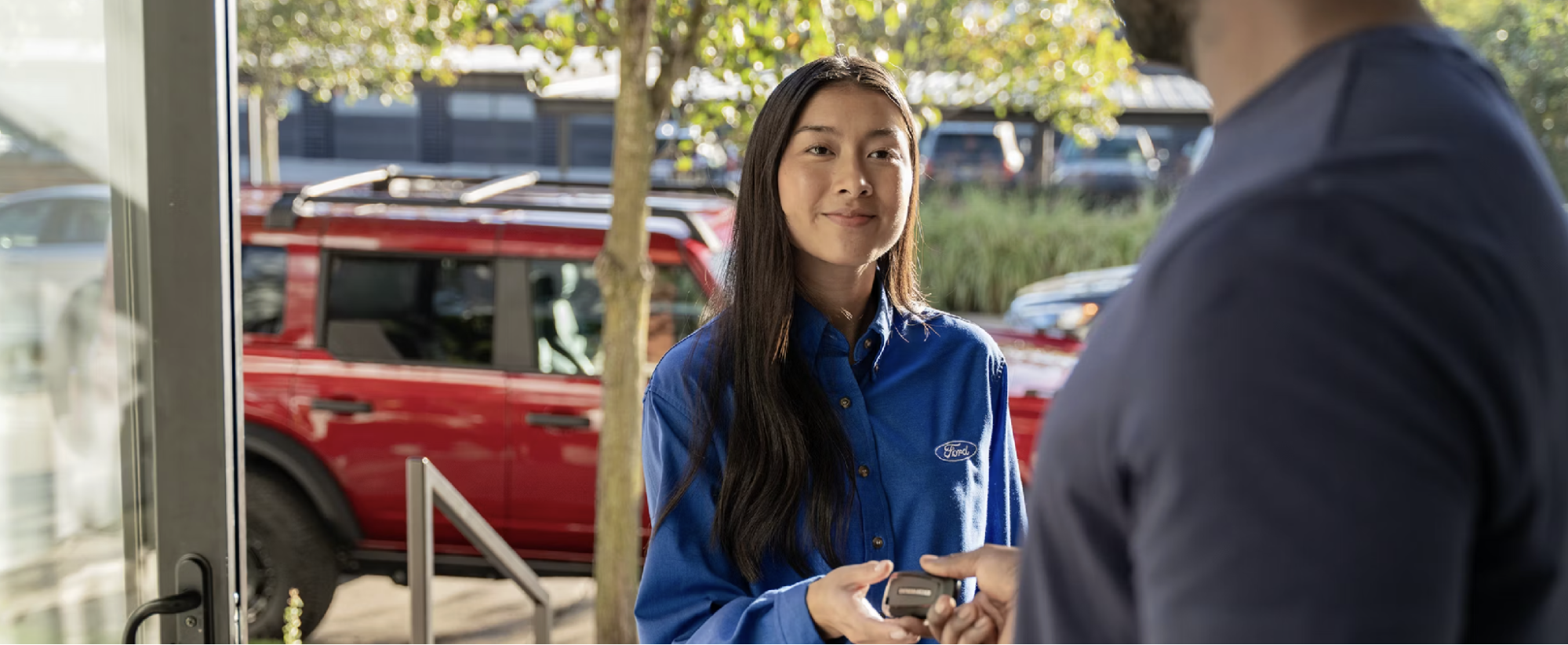 Ford service advisor handing car keys to a customer during a Ford Pickup & Delivery appointment
