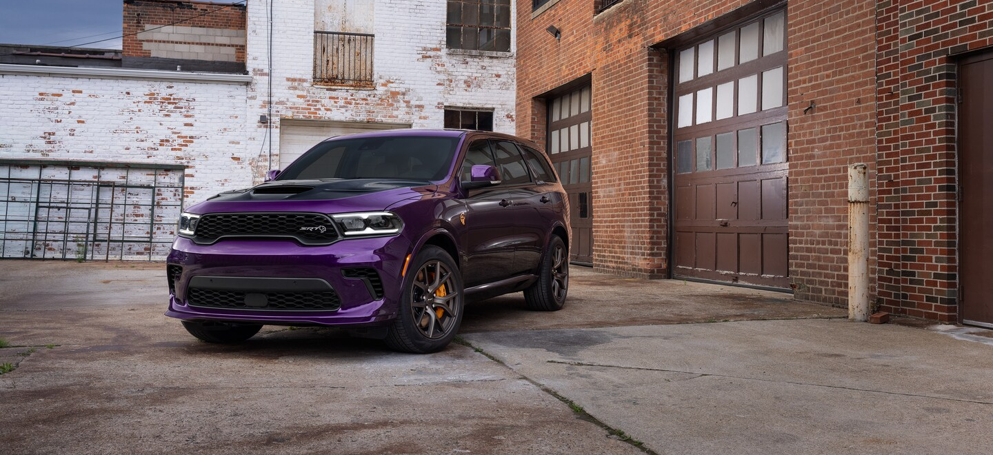 Purple Dodge Durango parked by a garage