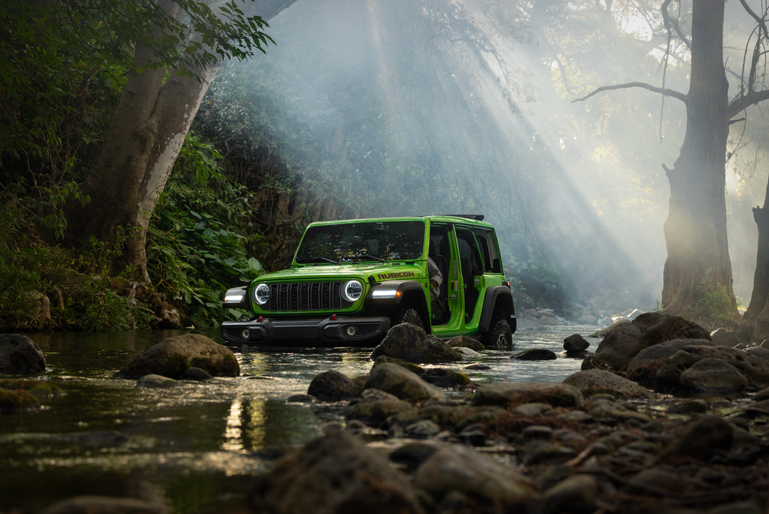 Green Jeep Wrangler 4-door on a rocky forest stream bed