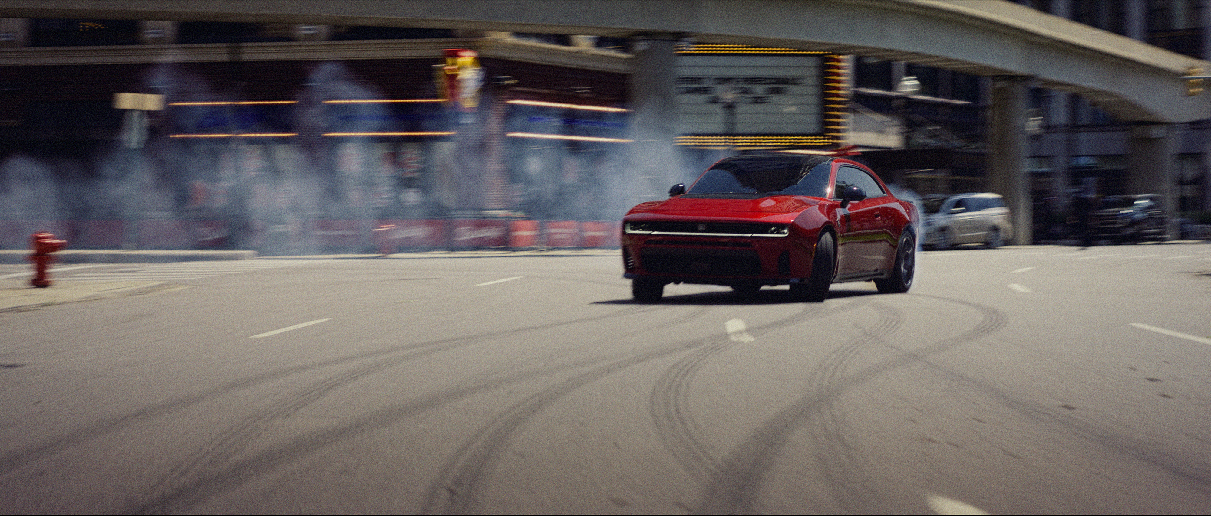 Red Dodge Charger driving under an overpass