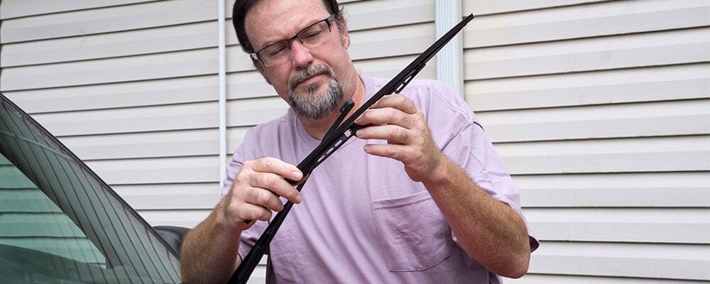 Man changing wiper blade on vehicle