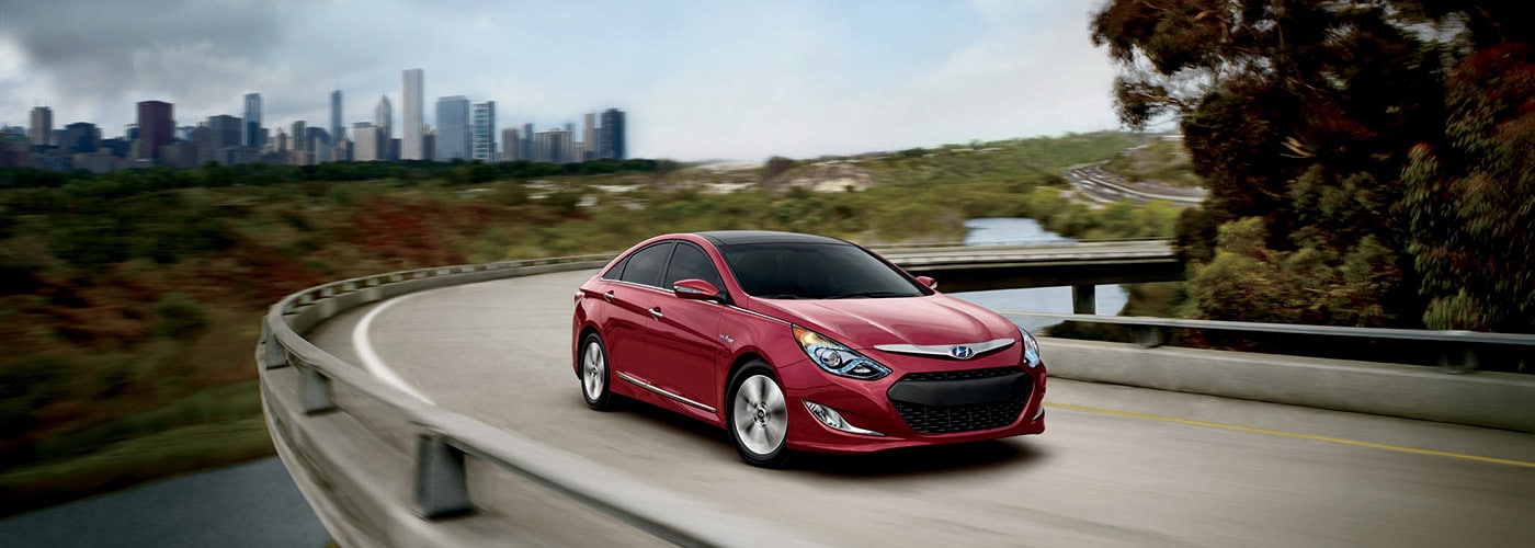 2014 Hyundai Sonata Hybrid in red driving on curved bridge