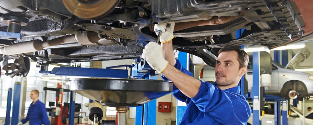 Auto mechanic at car suspension repair work
