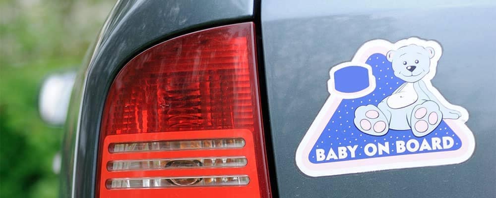 Faded baby on board sticker that needs removed from the bumper of a blue car