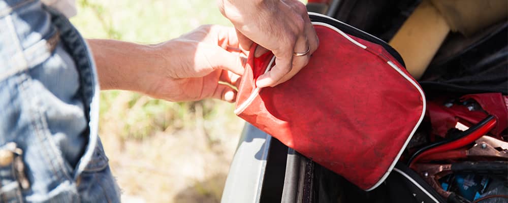 Man removing emergency preparedness kit from back of car