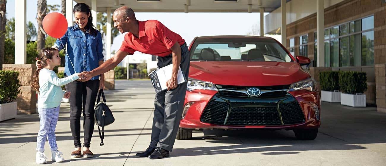Toyota Advisor shakes hand of child with mom standing near