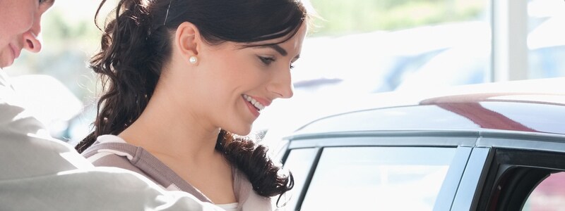 Car dealer pointing the interior of a car